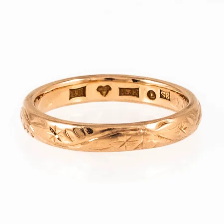 Ring i 18K guld med utvändig mönstergravyr. Den är i storlek 16¾, är 3,2 mm bred, 1,7 mm hög och väger 3,9g. Stämplad S8 (1944), JP (Juvelerare AB J. Petterssons Eftr, Stockholm), 18K, kattfot.