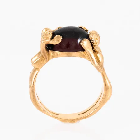 Ring "Zornringen" mellan i 18K guld med en röd (syntetisk) cabochonslipad sten 10 x 12 mm. Den är i storlek 18, är 4,5 - 11,5 mm bred och väger 11,2g. Nypris c:a 31.500 kr. Stämplad RGA (Dala Guldsmide AB, Rättvik). Svaga repor på stenen, men fin lyster ändå. 