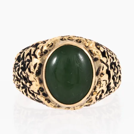 Doserad ring i 14K guld med en grön cabochonslipad sten 11,5 x 9,5 mm. Den är i storlek 18½, är 3 - 15mm bred och väger 8,6g. Gravyr. 