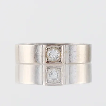 Ring 18k vitguld med solitär diamant på 0.18 ct enligt inskription,guldsmed Gunnar Vettholm Varberg 2011, storlek 15 ¾ mm ojämn form,bredd 4.5 mm. Vikt: 4,5 g