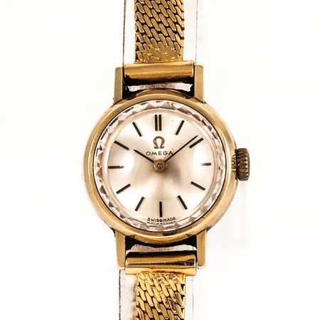 Damur Omega i 18K guld med band i 18K. Boett Ø 19,5 mm, manuell, safirglas. Innermått 17,5/18 cm Bruttovikt: 22,8g. Veck i bandet. Nött krona.