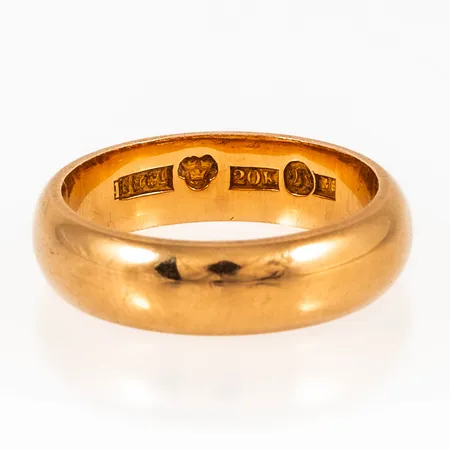 Ring i 20K guld. Den är i storlek 17½, är 5,3 mm bred, 2 mm hög och väger 7,9g. Stämplad R6 (1895), H&Co (F.Holm & Co, Vänersborg), 20K, kattfot. Gravyr initialer. 