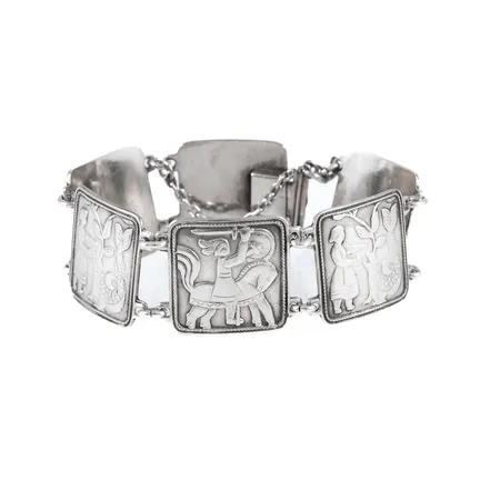 Armband i silver med människo- & (sjöo)djurmotiv i relief. Design David Andersen, Norge. Det är 25 mm brett, 19 cm långt och väger 42,2g. Kistlås & säkerhetskedja. 