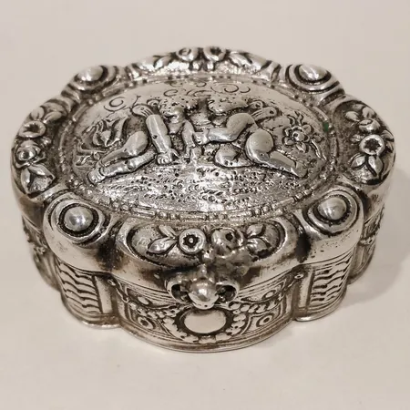 Dosa med mönster av två änglar i relief längd 55mm bredd 42mm, gravyr silver Vikt: 44,6 g