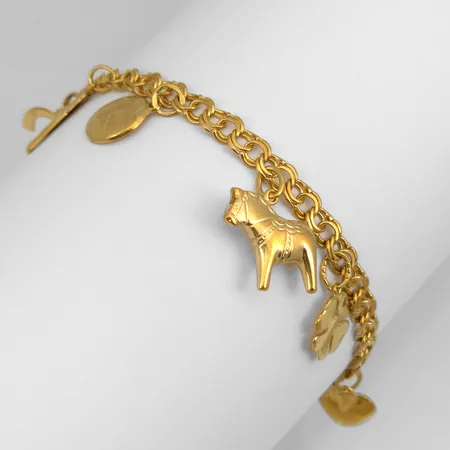 Armband Bismarck med åtta berlocker, 18K guld, Hildens Guldvaror Ab (SOH), Sala, svensk kontrollstämpel, längd knäppt 19,0 cm, bredd 4,5 mm, berlocker med varierande mått, berlock volleyboll med gravyr och ojämnheter på baksidan, berlock hjärta med små ojämnheter, för övrigt i fint skick Vikt: 11,6 g