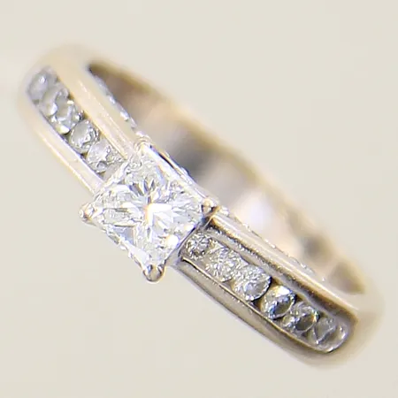 Ring med diamanter 1 x ca 0,59ct prinsesslipad kvalitet ca Top Crystal (I)/P, fjädrar som når ytan, 26 x ca 0,005ct, 12 x ca 0,02ct, 2 x ca 0,01ct, stl:17 bredd 3,5-5mm, vitguld 18K Vikt: 4,6 g