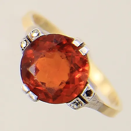 Ring med troligen spessartit samt markasiter stl:15¼ bredd 1,5-10mm svensk importstämpel, en markasit saknas, fattningsdel i silver, mittensten sitter något löst, stenar med slitage samt nagg, något skev skena, skena i 18K  Vikt: 2,5 g