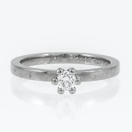 Ring med en briljantslipad diamant 0,17ct ca W(H)/si stl:16 bredd 2-4,5mm, höjd 1,8mm, gravyr, vitguld 18K 3,3g. Stämplad GIU (Guldsmedjan i Umeå AB, Umeå), 18K och kattfot.