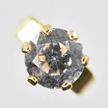 Ring med vit sten och hög fattning stl 14¼, bredd 2-10 mm, fattningens höjd 7 mm, sten sitter löst, 18K. Vikt: 2,6 g