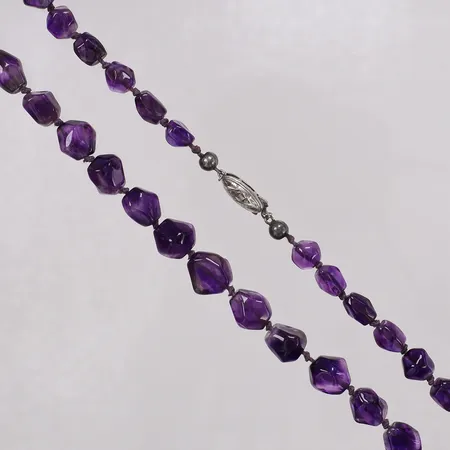 Collier med doserade ametister, längd 55cm, bredd 7,5-11,3mm, flertal stenar med skador, felstämplat, skevt lås  i vit metall.  Vikt: 0 g