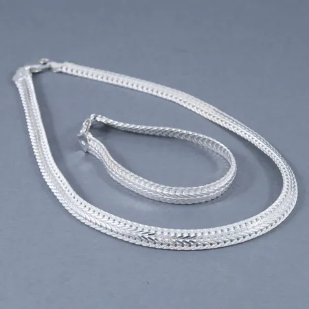 Set i halvstelt delvis matterat silver. Collier 42 cm, armband 20 cm. Bredd 8,2 mm. Stämplat 925. Framstår oanvänt. Vikt: 50,9g.