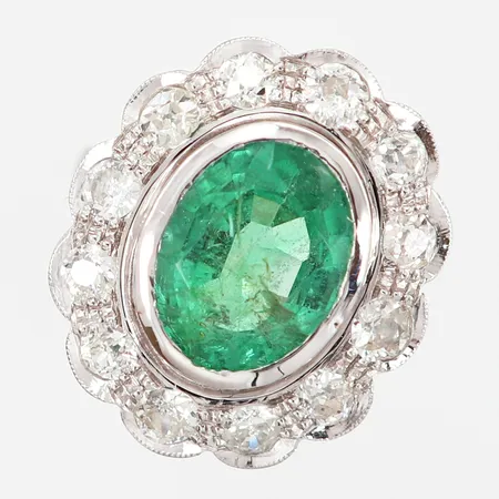 Ring med oval facettslipad smaragd ca 5.50ct ca 13,4x10,9x6,5mm, samt gammalslipade diamanter 12 x ca 0,10ct, kvalitet ca F-I/VS-I, stl:18, fattning 22x19mm, en diamant med naggad rondist, vitguld, 18K Vikt: 5,4 g