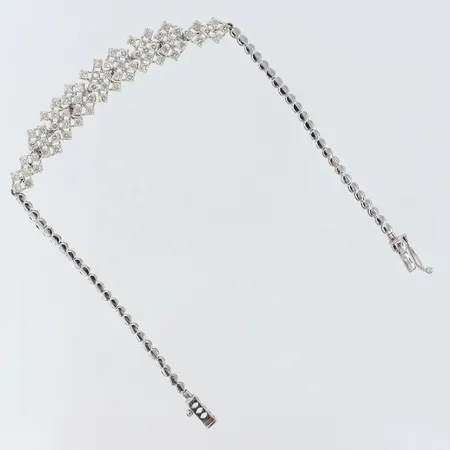 Armband med diamanter ca 64 x ca 0,03ct totalt ca 1,90ctv Kvalitè Cr-Ca(J-N)/SI längd 19,5cm bredd 2,2-9mm fåtalet diamanter indikerar på syntetiska en diamant saknas 18K. Vikt: 8,4 g
