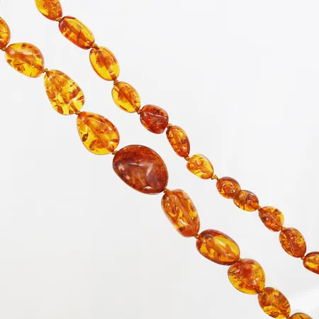 Collier med bärnsten längd ca 62cm, bredd 12-25mm, varierande form, utan lås