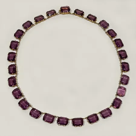 Collier med 27st lila glasstenar, 44cm bredd ca 9mm tillverkad av Dufva A G år 1922 18K bruttovikt 57,1g Vikt: 57,1 g