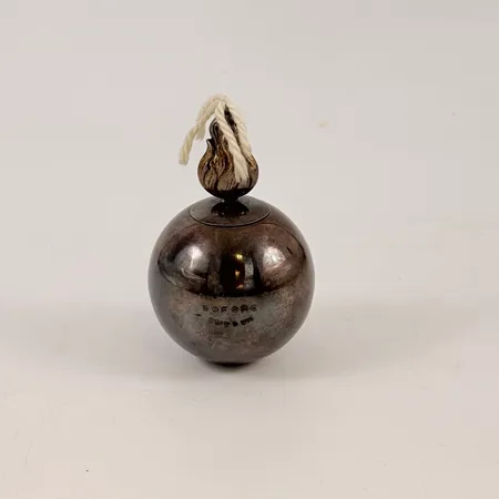 Oljelampa i silver, I form av granat. Lock med bajonettfäste samt veke. Gravyr på livet 'Nobel Bofors Sweden' Ø62,6mm, höjd på pipen ca 34,7mm, Tillverkad av Tesi 1963. tygnd botten, bruksslitage/repig, bruttovikt 264,1g, 830/1000 silver. Skickas med paket.