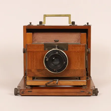 Fältkamera, mahogny samt gulmetall, 1910/20-tal, höjd 14cm, filmkassetter saknas, ej funktionstestad, bruksslitage, optiken med dimma/smuts.  Skickas med postpaket.
