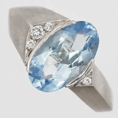 Ring med ovalslipad akvamarin 7x14mm samt diamanter 1 x ca 0,03ct, 3 x ca 0,01, stl 19, bredd 4-14mm, matterad yta, nagg på sten samt skena, vitguld, 18K. Vikt: 11,3 g