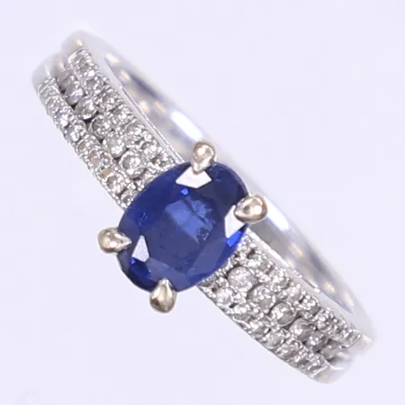 Ring med diamanter 14x ca 0,01ct 32x ca 0,005ct samt blå safir ovalslipad 1x ca 0,70ct stl:17, bredd 2,5-7mm, i behov av omrodiering, smärre bruksslitage, små nagg på safir, GHA, vitguld 18K Vikt: 4,2 g