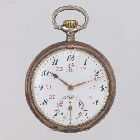 Fickur Omega 51mm, rött 24-timmarsindex, boettnr: 5793946, innerboett i silver, verknr: 4972440, tidigt 1900-tal, slitet index med färgbortfall, skadad emalj, sprickor, slitage, bucklor, monogramgravyr, klockkedja i oädel metall, bruttovikt: 103,5g Vikt: 117,1 g