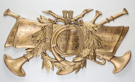 Dörröverstycke, 1800-talets andra hälft, bemålad och bronserad, dekor av musikinstrument och noter, höjd 71cm, bredd 139cm,  åldersbetingat slitage, sprickor.  Specialfrakt, kontakta pantbankskontoret för mer information.
