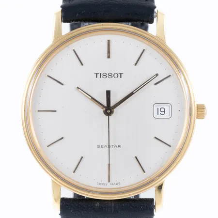 Herrur Tissot Seastar i 18K guld med svart läderband (original). Boett Ø 33,5 mm, datum, quartz, gravyr "För nit och redlighet i rikets tjänst", enstaka repa på plexiglas. Annars i fint skick. Går ej - Batteribyte krävs? Bruttovikt: 29,4g. 