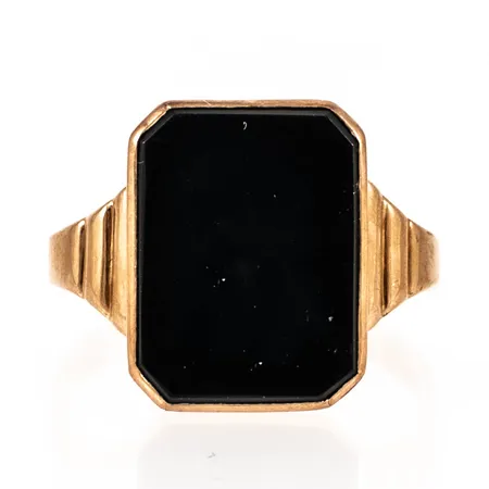 Klackring i 18K guld med svart sten (sannolikt onyx eller agat). Den är i storlek 20, är 2,5 - 16,5 mm bred och väger 4,1g. Stämplad A9 (1951), W&A (Wiktorsson & Arnesson Sävsjö Guldsmedsbolag, Sävsjö), 18K och kattfot. 