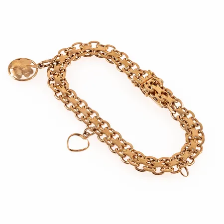 Armband X-länk i 18K guld med två berlocker: Fyrklöver, hjärta. Det är 19,5 cm långt, 8 mm brett och väger 21,2g. Kistlås. Lös ögla från berlock hänger kvar. 