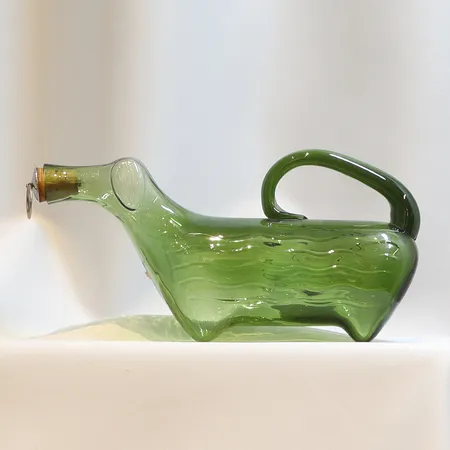 Karaff "Fyllehund" i grönt glas med propp i vitmetall, längd 27 cm höjd 12cm med slitage, 1900-tal  Skickas med paket.