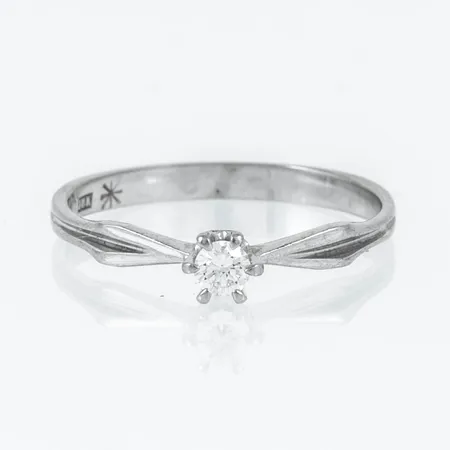 Ring Stjärnringen Capella i 18K vitguld med 1 x 0,09ct briljantslipad diamant. Den är i storlek 17, är 2,1 - 3,8 mm bred och väger 1,6g. Nyvärde c:a 12.500.-. Stenstorlek 0,09ct ingraverad. Stämplad HS (Hans Strömdahl, Stockholm), 18K, kattfot och stjärnringenstjärna. 