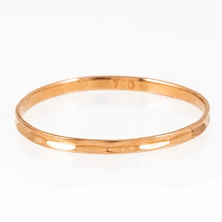 Ring i 18K guld med fasetterat mönster. Den är i storlek 18, är 1,4 mm bred, 0,5 mm hög och väger 0,5g. Något ojämn skena. 