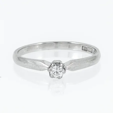 Ring i 18K vitguld med 1 x 0,10ct briljantslipad diamant. Den är i storlek 16, är 1,7 - 3,5 mm bred och väger 1,7g. Stenstorlek 0,10ct ingraverad. Stämplad N9 (1963), 18K och kattfot. Slitna klor. 