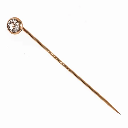 Nål i 18K guld med vit sten. Den är 5,5 mm bred, 46 mm lång och väger 0,7g. 