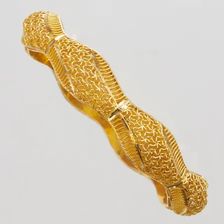 Armring med genombruten dekor yttre Ø70mm, innre Ø58mm, bredd 7-11,5mm, 18K Vikt: 12,1 g