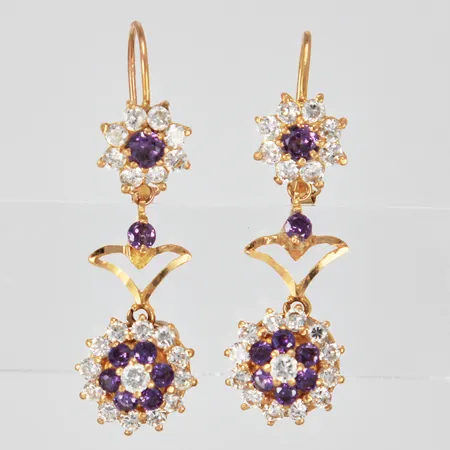 Ett par örhängen med vita och lila stenar längd: ca 3,8cm bredd: ca 1-12mm en lila sten limmad ostämplad 18K Vikt: 6,8 g