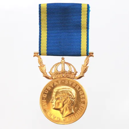 Medalj i 23K med krona i 18K, Ø27mm, inkl band, etui. Vikt: 14,8 g