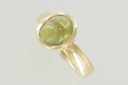 Ring med ljus grönsten stl:19½ bredd 4-12 mm, svensk tillverkad Frembergs Guldsmedja AB i Karlshamn, graverad 18K Vikt: 8,9 g