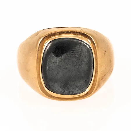 Klackring i 18K guld med en repig hematit. Stl:20½. Bredd 3,7 17,6 mm. Defekt- sprickor i skenan. Vikt 10,6g Vikt: 10,6 g