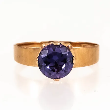 Ring stl:18½ med lila syntetisk sten, bredd 2,5-9mm, några nagg på fasetterna, men annars fin lyster, 18K 2,8g. 