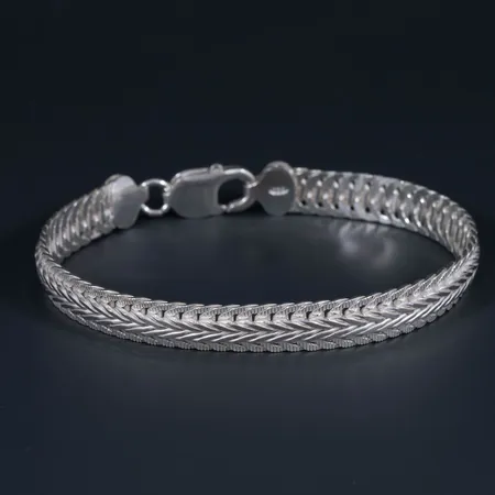 Oanvänt halvstelt armband i delvis mönstrat silver 925/1000. Längd 20 cm, bredd 8,3 mm. Karbinhake. 16,6g.