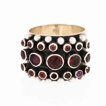 Ring KumKum i silver med röda stenar. En sten sitter snett. Stl:18. Bredd 10,5 - 16 mm. 15,6g 925/1000. 
