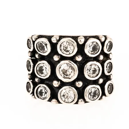 Ring i silver med vita stenar. Stl:19. Bredd 9 - 19 mm. 15,2g 925/1000. Lite ojämn skena.