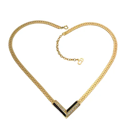 DESIGN CHRISTIAN DIOR Vintage Collier, integrerat hänge med svart emalj/vita stenar (s.k. Rhinestones), hänge V-formad modell, förgylld metall, längd 38-43 cm, kedja bredd 4,4 mm, avslutande charm med logga CD, stämplad på både hänge och charm "Chr.Dior & copyright symbol", stenar utan anmärkning, fint skick, förefaller sparsamt använd, vikt 16,7 gram