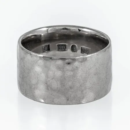 Umeåtillverkad ring med hamrad yta stl:16½ (mätt i mitten på ringen) bredd 10,5mm, stämplad L11 (2009), GIU (Guldsmedjan i Umeå AB, Umeå), vitguld 18K 12,3g. 