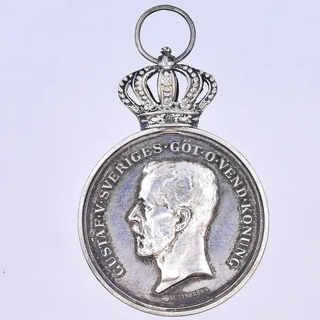 Medalj Gustaf V längd 58 mm, bredd 36 mm silver 830/1000. Vikt: 20,5 g