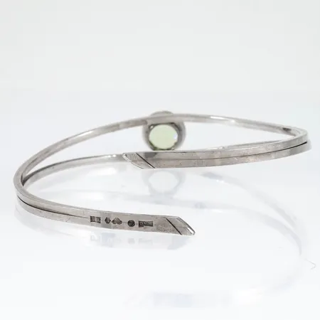 Stelt armband med ljusgrön sten (syntetisk) innermått ca 19cm bredd 3,5-11mm, stämplad Q9 (1966), HAÖ (Öhmans Eftr P. Aug, Lycksele), kattfot, silver 14,8g.