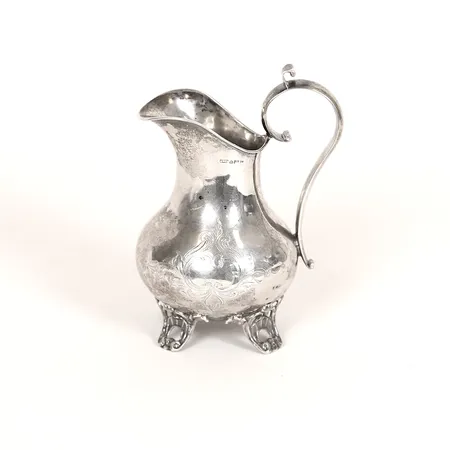 Gräddkanna med dekor i relief, höjd 13cm, bredd ca 10cm, gravyr på undersidan, troligtvis Vimmerby 1878, bucklor, silver 830/1000. Vikt: 80,6 g