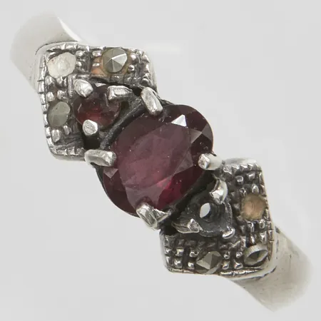 Ring med en granat ca.7x5mm en mindre granat samt markasiter, stl:18¾, bredd: 2,8-7,8mm, några stenar saknas, silver 925/1000 Vikt: 4,6 g