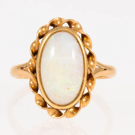 Ring med vit solid opal ca 12x7,5mm stl:16½ bredd 2-17mm, stämplad Y8 (1949), BRL (Bröderna Lundqvist AB, Falun), kattfot 18K, svag spricka i sten. Vikt: 2,9g.
