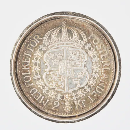 Lock med infällt mynt 2kr år 1940, Gustaf V, Med folket för fosterlandet, Ø34mm, höjd 7mm, silver 800/1000 Vikt: 19,6 g